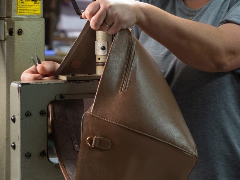 Costureira da Edubolsas costurando uma bolsa de couro caramelo na máquina