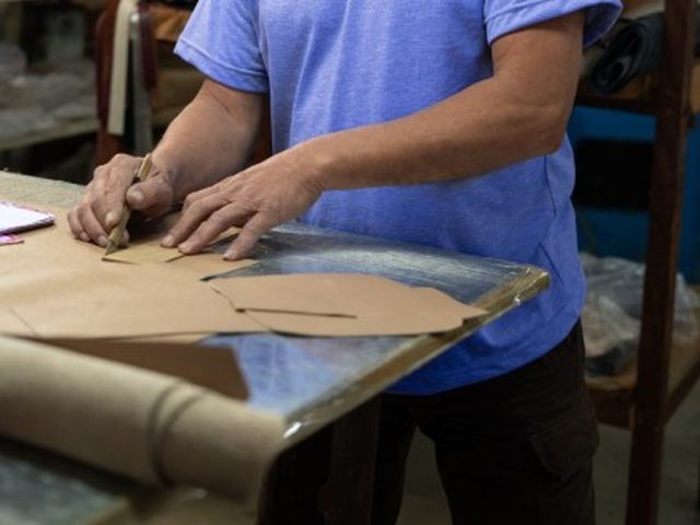 Artesão da Edubolsas riscando o molde de uma bolsa no papel