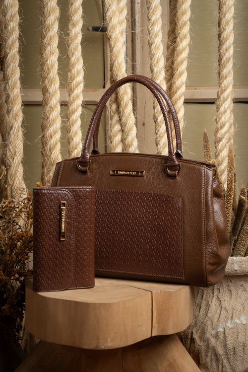 Bolsa de couro marrom com bolso frontal de textura trançada e a carteira com a mesma textura na frente